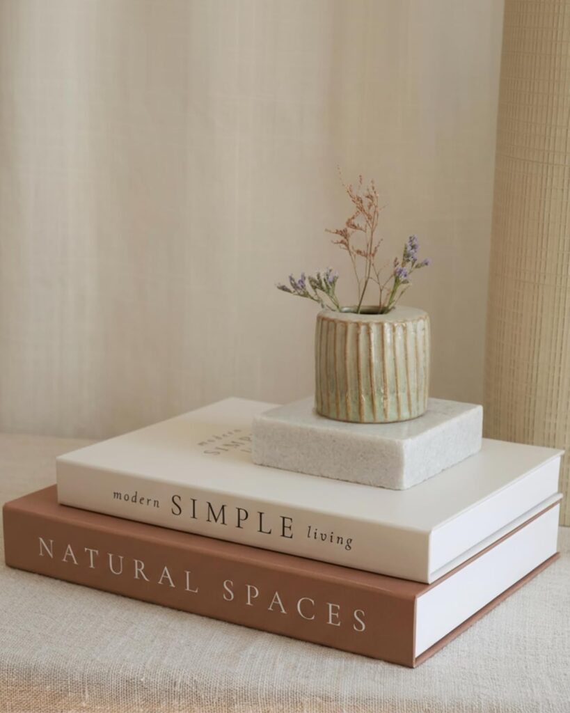 A stack of three linen-covered decorative books in neutral beige and white tones, used for aesthetic shelf styling.